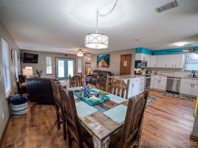 dining area with ceiling fan, french doors, wood-type flooring, and a textured ceiling