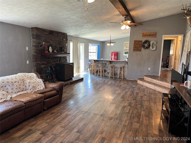 living room with vaulted ceiling with beams, ceiling fan, dark hardwood / wood-style flooring, and a textured ceiling