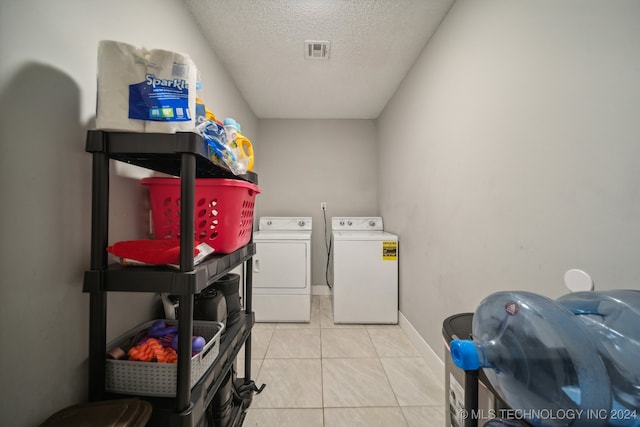 laundry area with a textured ceiling, light tile patterned flooring, and washing machine and clothes dryer