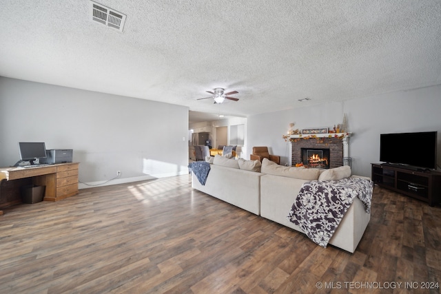 living room with dark hardwood / wood-style floors, a textured ceiling, a fireplace, and ceiling fan