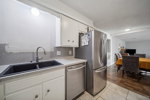 kitchen featuring white cabinets, a textured ceiling, light wood-type flooring, sink, and stainless steel appliances