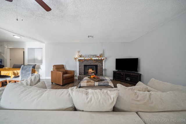 living room featuring a textured ceiling, hardwood / wood-style floors, a fireplace, and ceiling fan