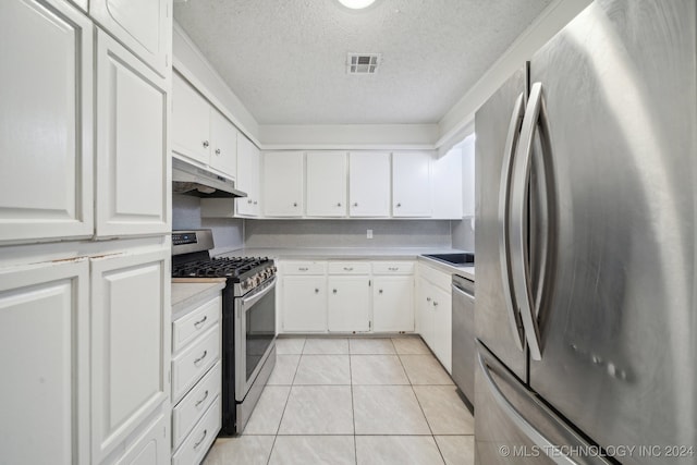 kitchen with appliances with stainless steel finishes, white cabinetry, a textured ceiling, and light tile patterned floors