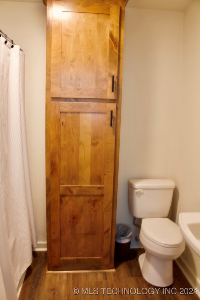 bathroom featuring toilet, a shower with curtain, and wood-type flooring