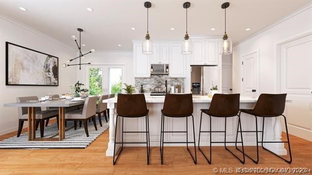 kitchen featuring ornamental molding, light hardwood / wood-style floors, white cabinetry, appliances with stainless steel finishes, and decorative light fixtures