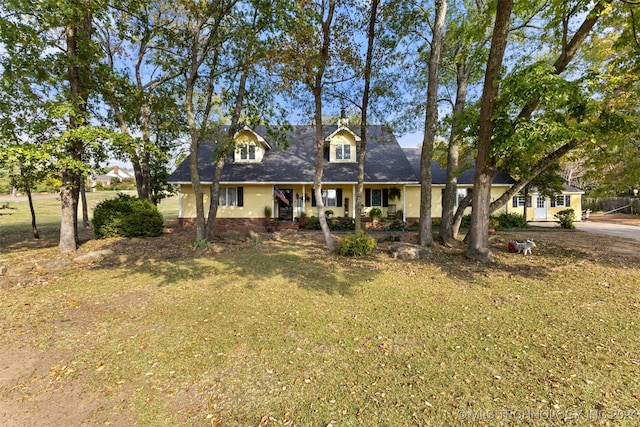 cape cod home with covered porch and a front lawn