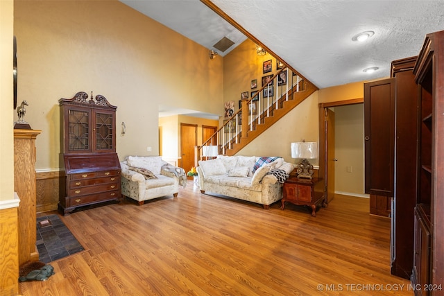 living room with crown molding, high vaulted ceiling, a textured ceiling, and hardwood / wood-style floors