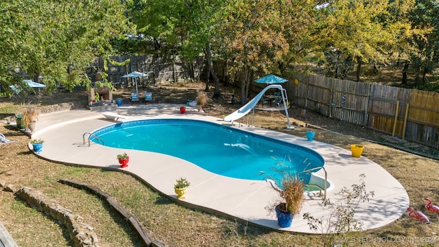 view of swimming pool featuring a water slide, a diving board, and a patio area