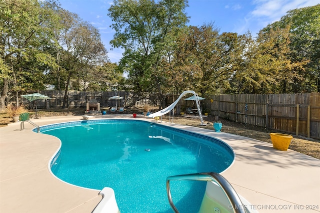 view of pool with a water slide, a diving board, and a patio area