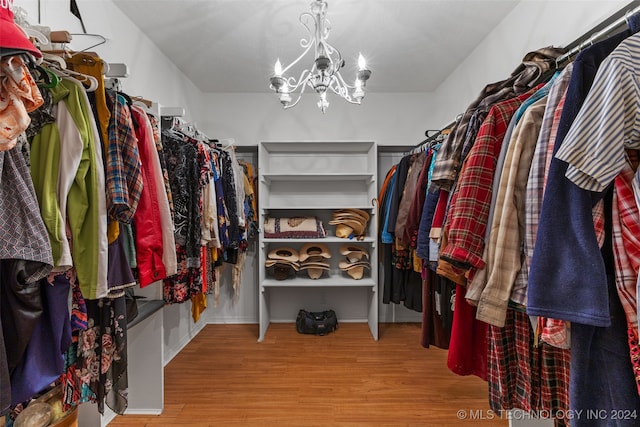 spacious closet featuring light hardwood / wood-style floors and an inviting chandelier