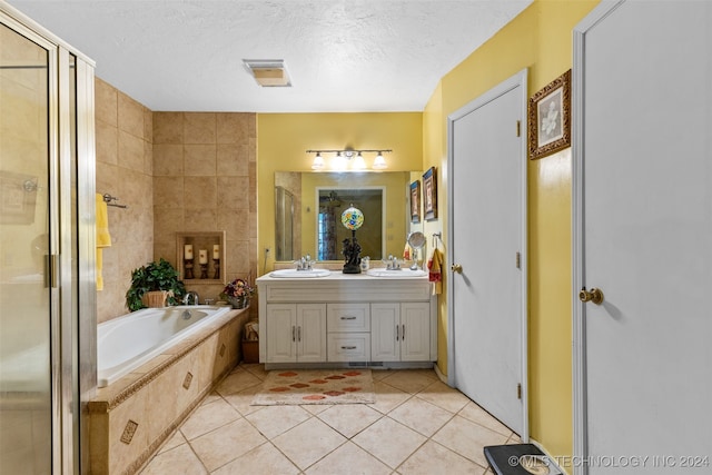 bathroom featuring vanity, a textured ceiling, tiled bath, and tile patterned floors