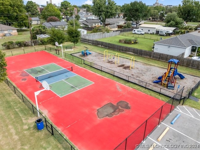 view of tennis court with a playground and a yard