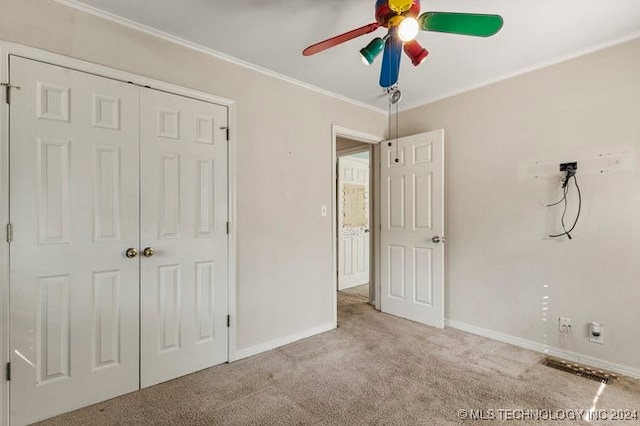 unfurnished bedroom with a closet, light carpet, crown molding, and ceiling fan