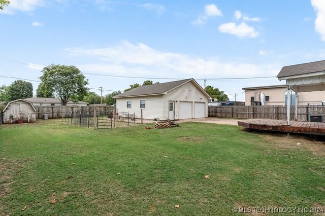 view of yard featuring a wooden deck, a storage unit, and a garage