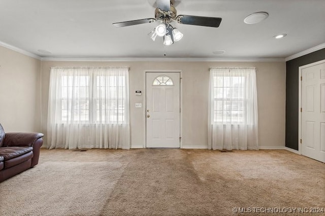 carpeted foyer with ornamental molding, ceiling fan, and a wealth of natural light