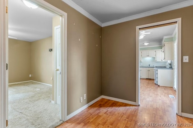 corridor featuring light wood-type flooring, crown molding, and sink