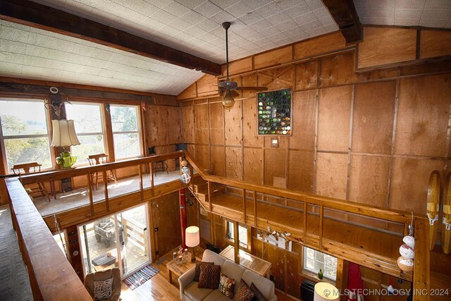 dining room featuring ceiling fan, vaulted ceiling with beams, wood walls, and hardwood / wood-style floors