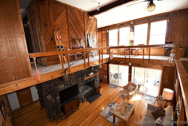 living room featuring beam ceiling, wooden walls, a fireplace, and hardwood / wood-style floors