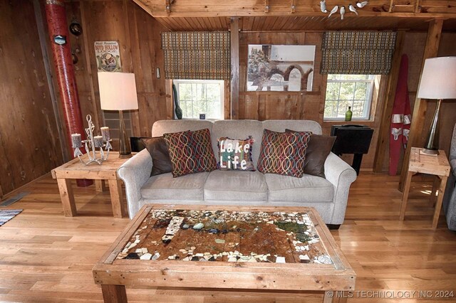 living room featuring hardwood / wood-style flooring, wooden walls, and beam ceiling