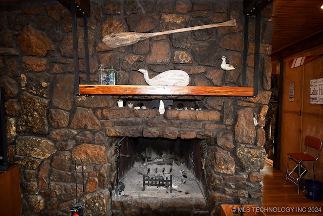 room details featuring a fireplace, wood walls, and hardwood / wood-style floors