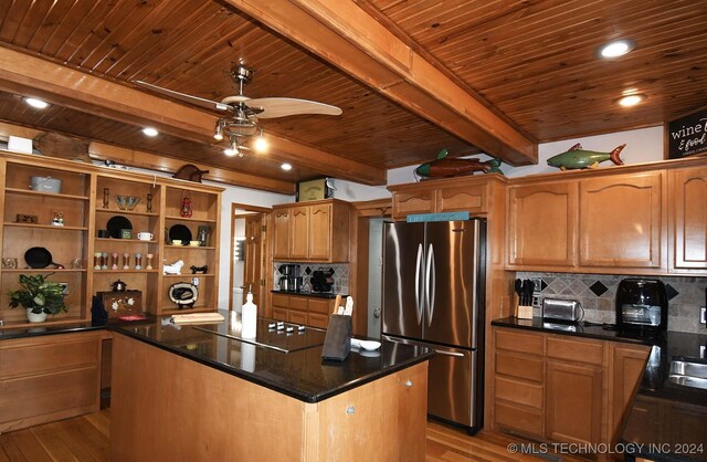 kitchen with stainless steel refrigerator, light wood-type flooring, beam ceiling, a kitchen island, and black electric cooktop