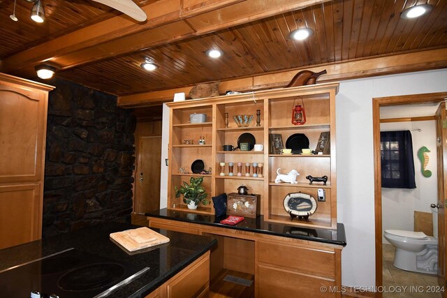 bar with wood ceiling, built in desk, black electric stovetop, dark stone countertops, and tile patterned flooring