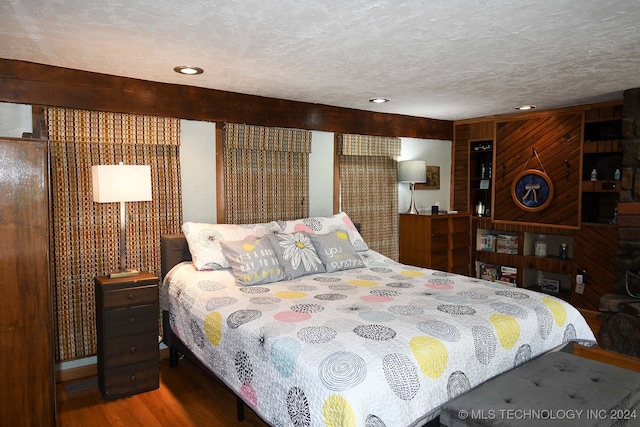 bedroom featuring wood walls, wood-type flooring, and a textured ceiling