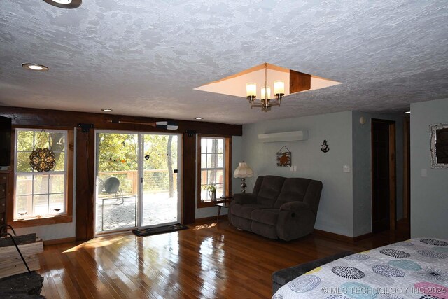 bedroom featuring a chandelier, access to outside, a wall mounted AC, hardwood / wood-style flooring, and a textured ceiling