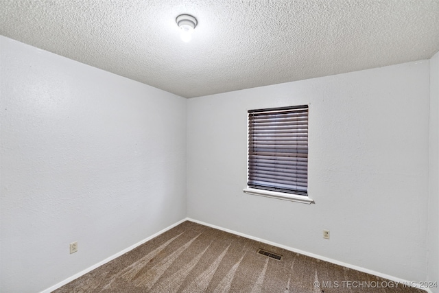 spare room with a textured ceiling and carpet