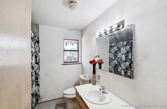 bathroom featuring tile patterned flooring, walk in shower, toilet, vanity, and a textured ceiling