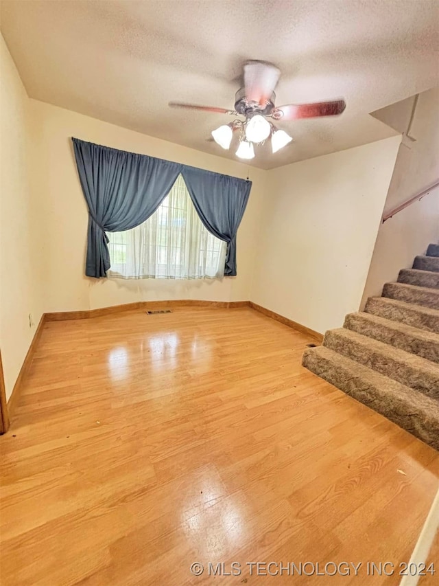 unfurnished room featuring ceiling fan, hardwood / wood-style floors, and a textured ceiling