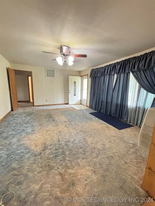 interior space with carpet flooring, a textured ceiling, and ceiling fan