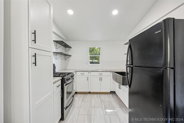 kitchen featuring lofted ceiling, white cabinetry, black refrigerator, and gas range