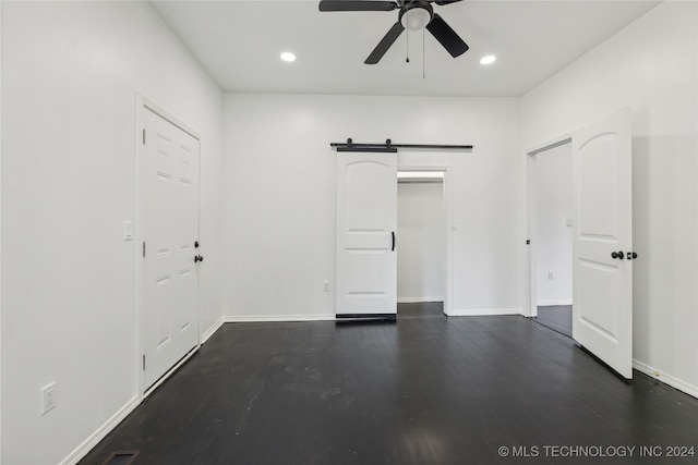 interior space with ceiling fan, dark wood-type flooring, and a barn door