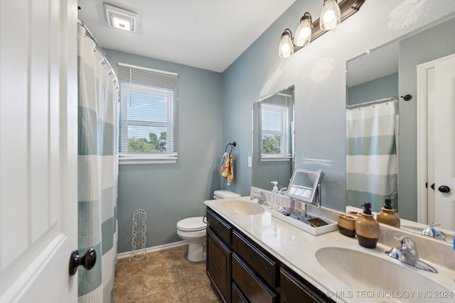 bathroom featuring vanity, toilet, tile patterned floors, and a wealth of natural light