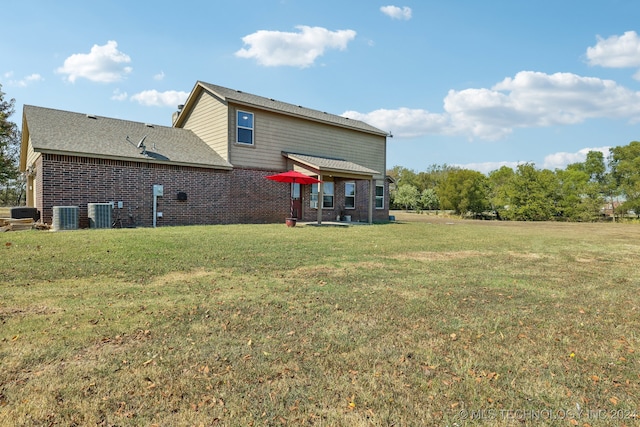 rear view of property with cooling unit and a lawn