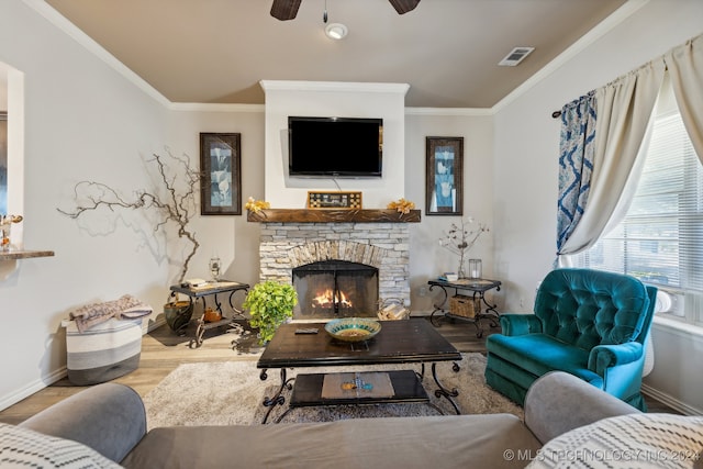 living room with crown molding, light wood-type flooring, a fireplace, and ceiling fan