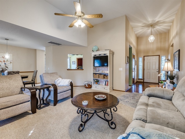 living room with ceiling fan with notable chandelier and a high ceiling