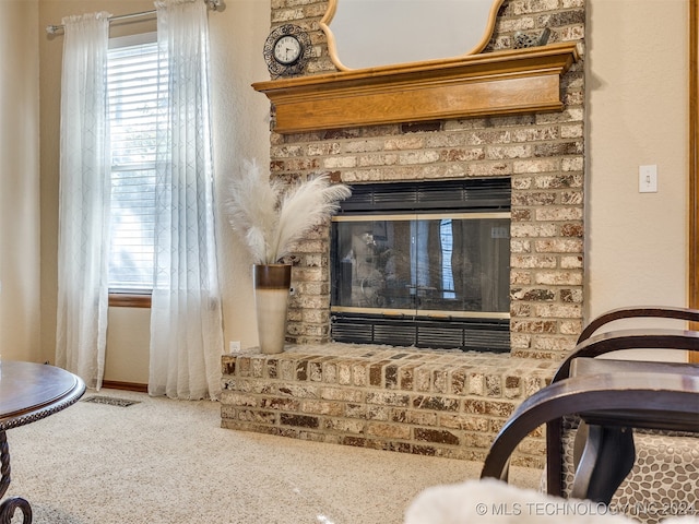 living area with a brick fireplace and carpet floors