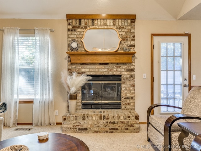 sitting room with a brick fireplace and light carpet