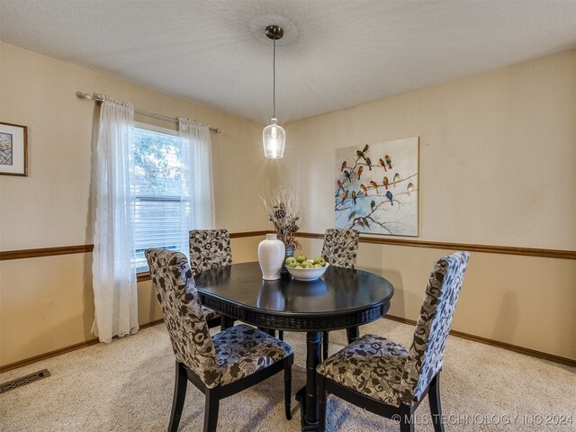 carpeted dining space with a textured ceiling