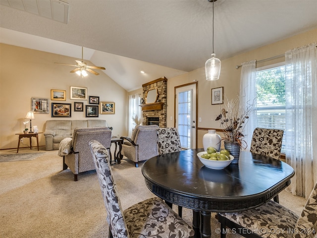 dining room featuring lofted ceiling, carpet flooring, a fireplace, and ceiling fan