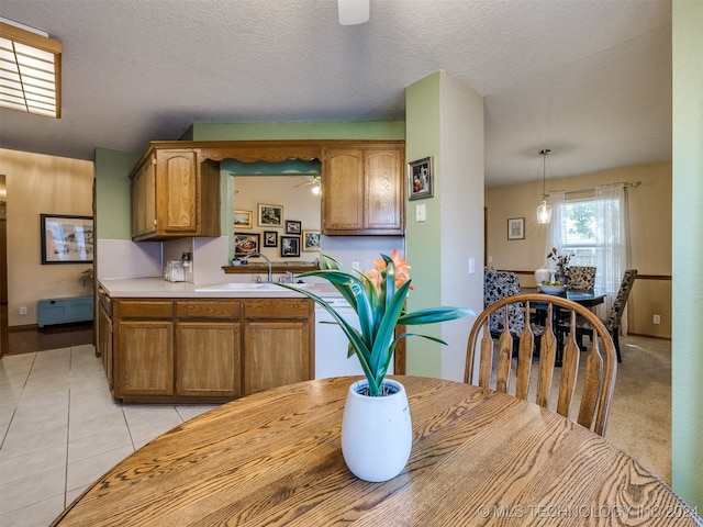 kitchen with light colored carpet, baseboard heating, decorative light fixtures, sink, and a textured ceiling