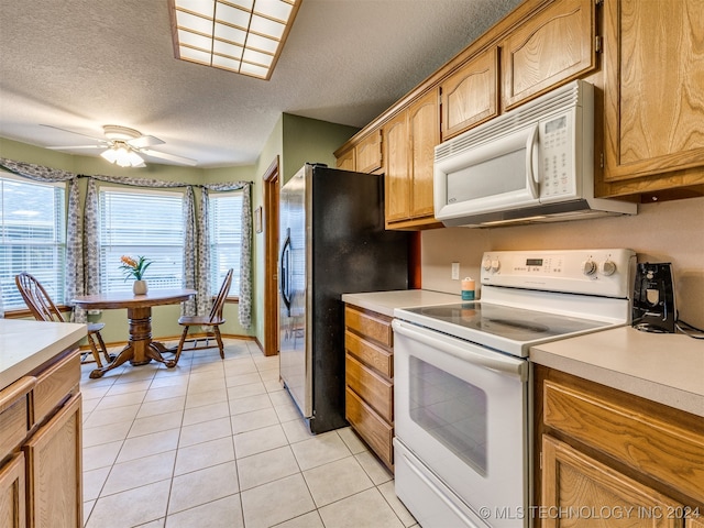 kitchen featuring ceiling fan, white appliances, light tile patterned floors, and a textured ceiling