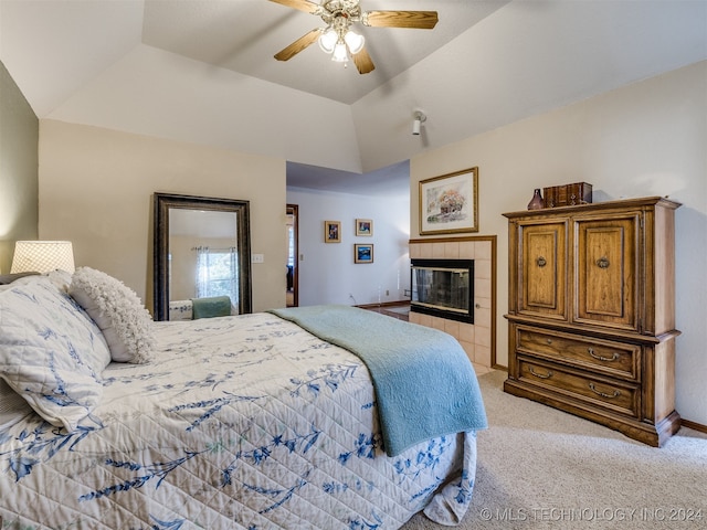 carpeted bedroom featuring lofted ceiling, ceiling fan, and a tile fireplace