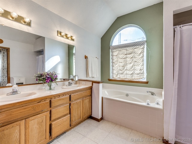 bathroom with lofted ceiling, tile patterned flooring, tiled tub, and vanity