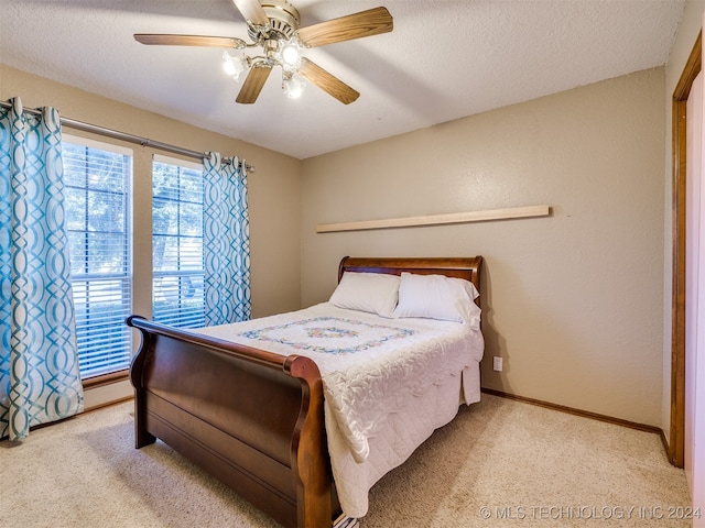 carpeted bedroom featuring ceiling fan and a textured ceiling