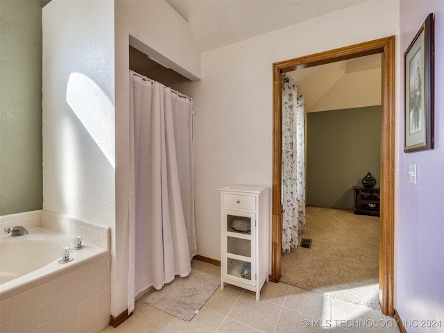 bathroom featuring tile patterned flooring, tiled tub, and vaulted ceiling