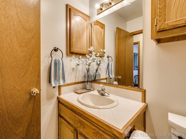 bathroom with toilet, vanity, and a textured ceiling