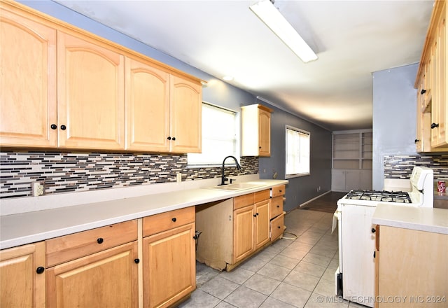 kitchen featuring sink, light brown cabinets, light tile patterned floors, white range with gas stovetop, and decorative backsplash